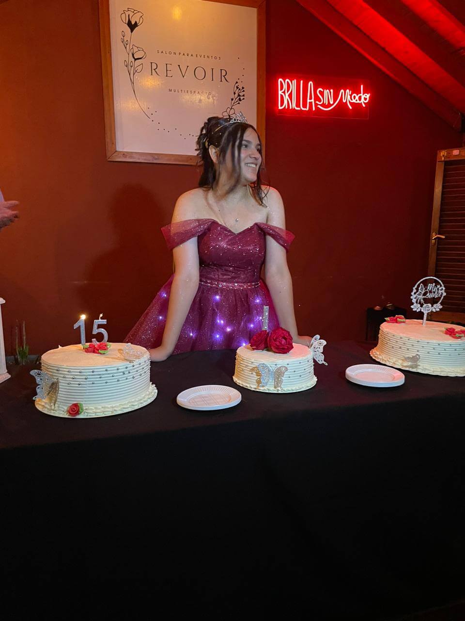 Quinceañera posando junto a sus tortas